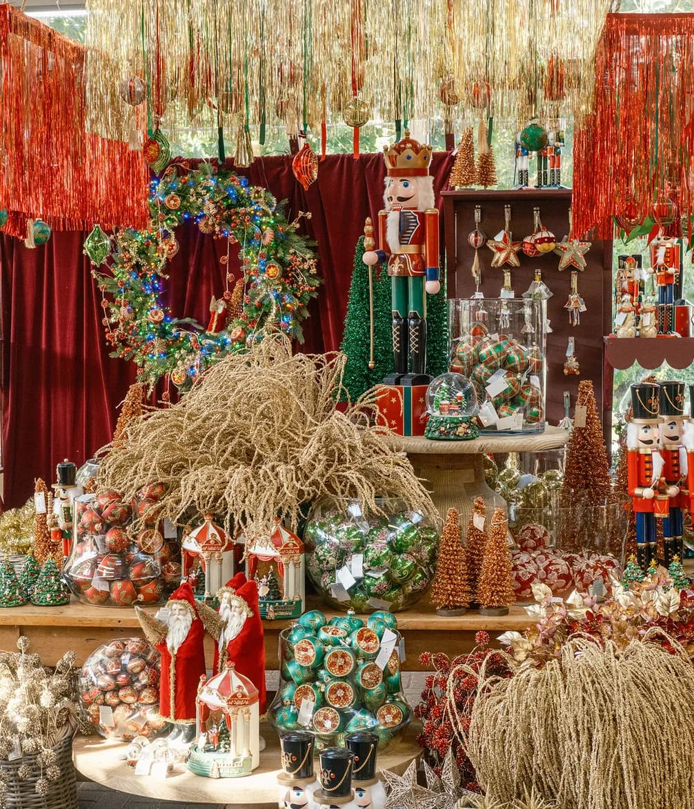 A vibrant Christmas display with large nutcrackers, illuminated wreaths, red velvet, and abundant ornaments in gold, red, and green.