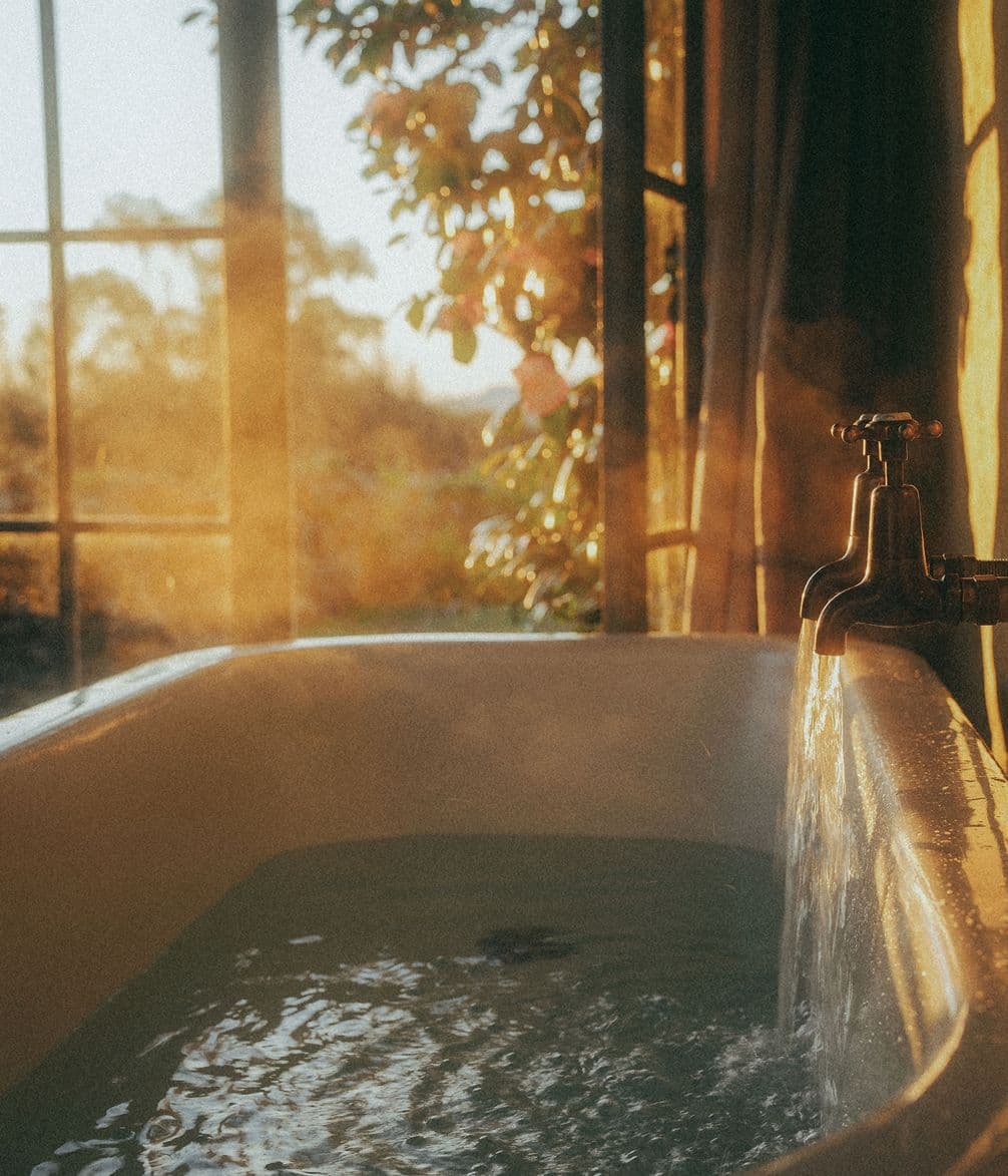 Steam rises from a bath with sunlight pouring through windows