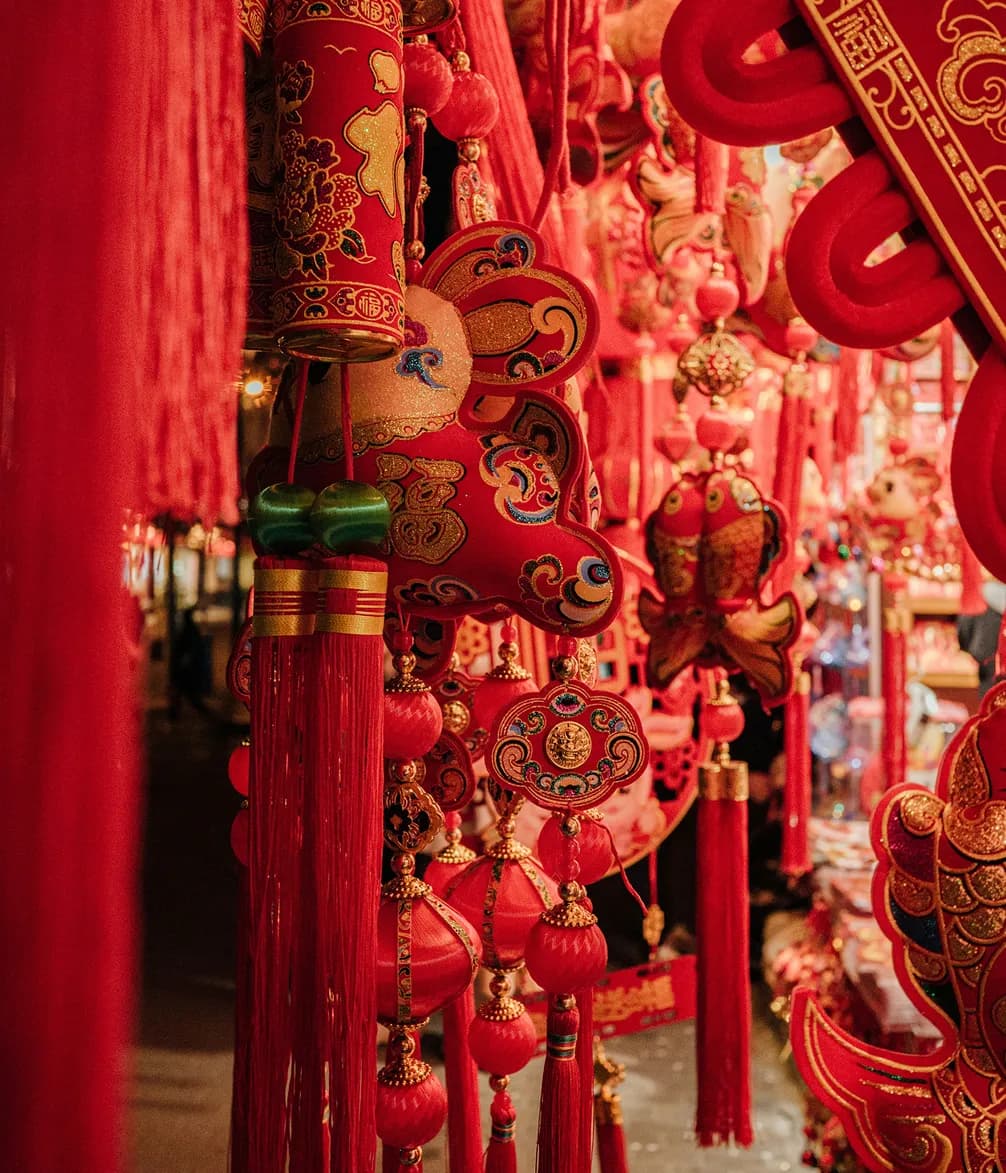 Red and gold Chinese New Year decorations featuring intricate patterns and tassels hanging closely together.
