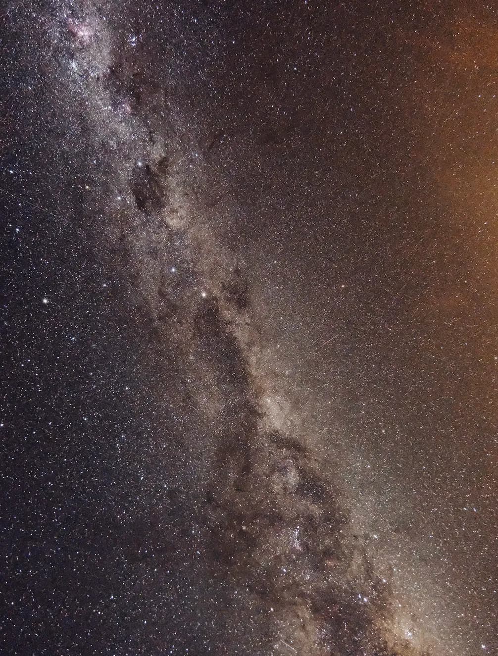 A starry view of the Milky Way galaxy with a bright cluster of stars and dust bands stretching diagonally across a dark night sky.
