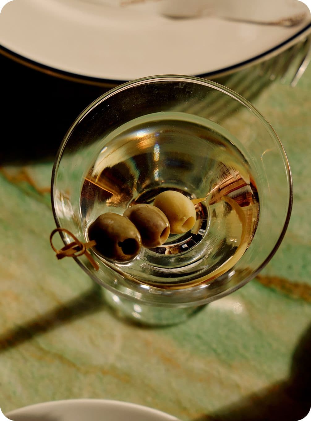 Aerial shot of a martini with three olives on a skewer
