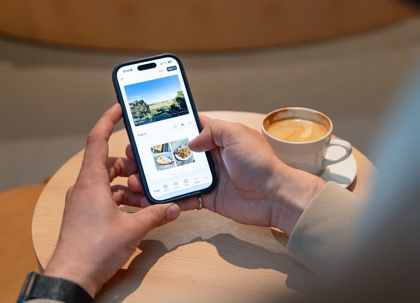 Person designing photo book with coffee on table