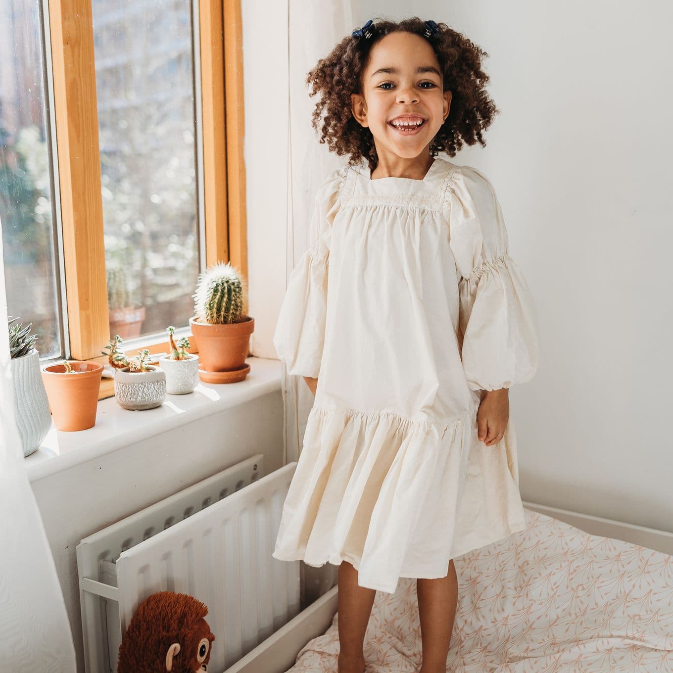 A schoolgirl smiles for the camera in a bright bedroom