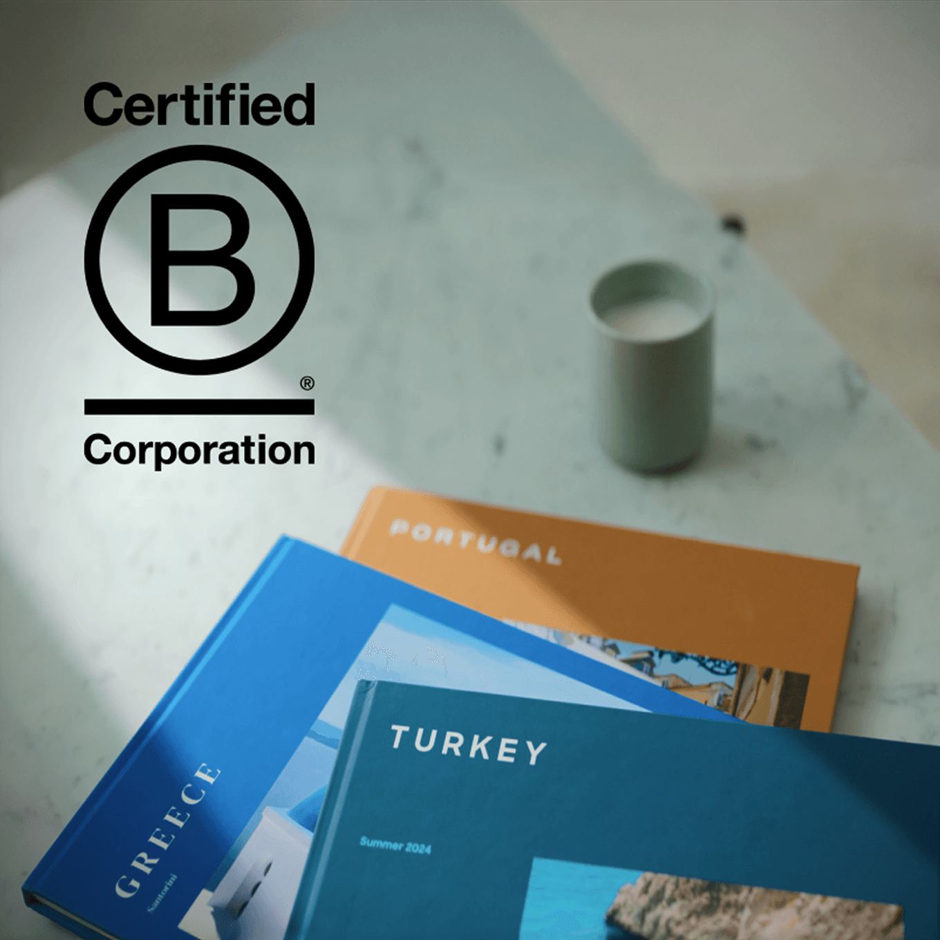 Popsa Photo Books stacked on a table with the Certified B Corporation logo imposed beside them
