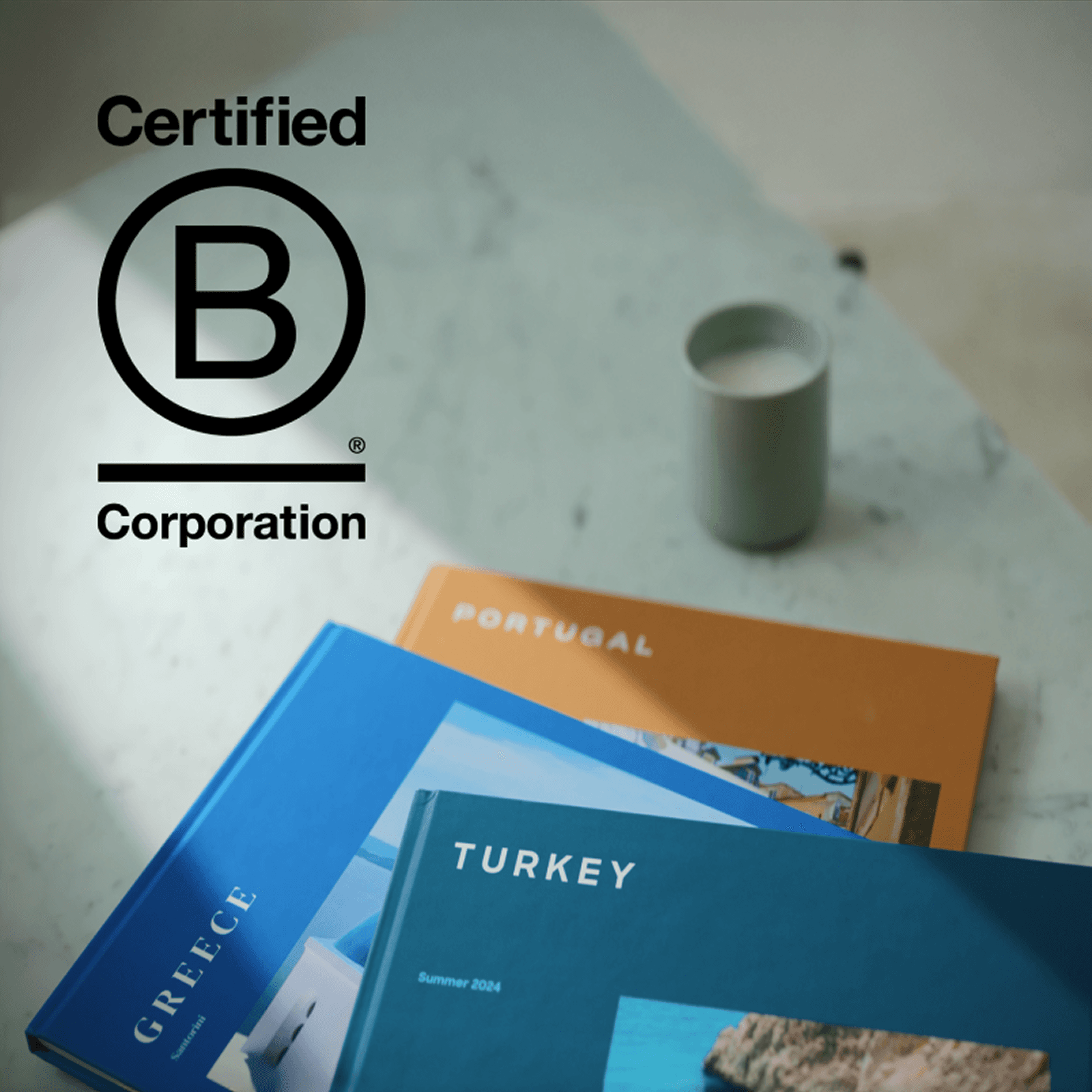 Popsa Photo Books stacked on a table with the Certified B Corporation logo imposed beside them