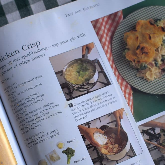 Open cookbook showing a chicken crisp recipe with steps and photos on a checkered tablecloth.