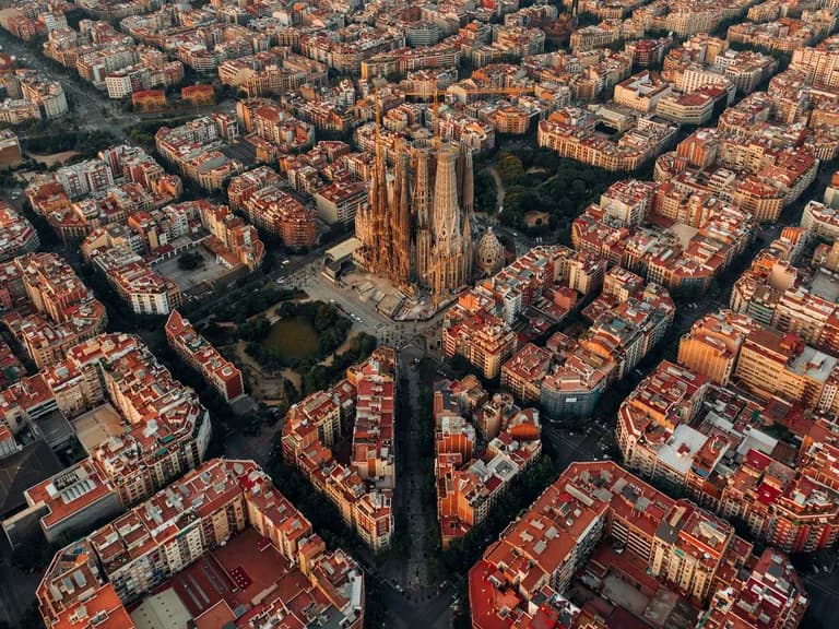 Aerial view of a city with a grid layout and a prominent cathedral in the center, surrounded by densely packed buildings.