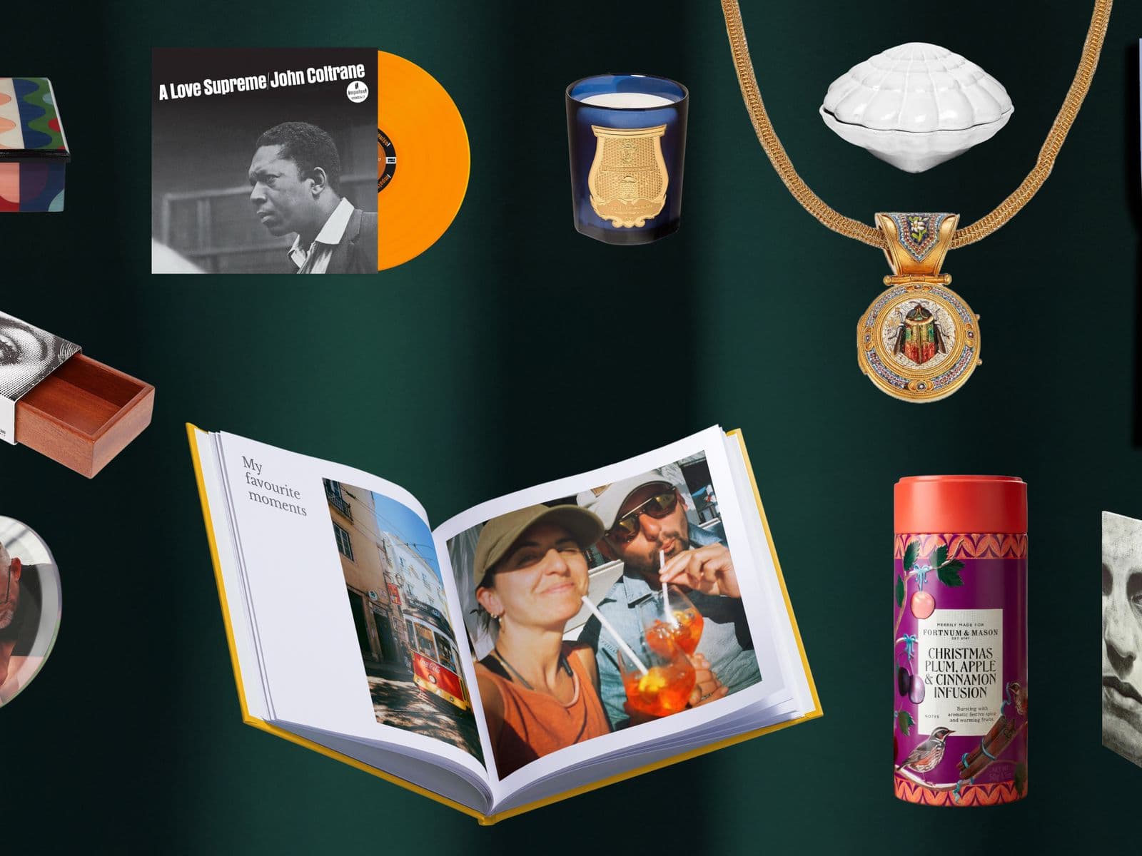 A collection of various gift items including a book, calendar, ornaments, a medal, and a record, arranged on a dark green background.