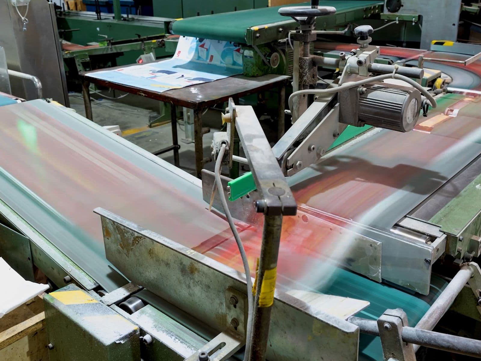 A factory conveyor belt system in motion, transporting printed materials through various machinery in an industrial setting.