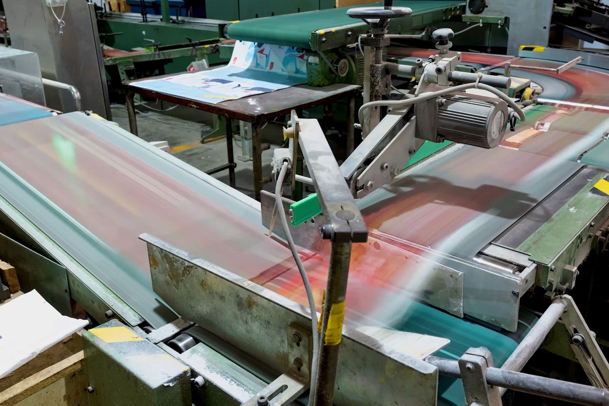 A factory conveyor belt system in motion, transporting printed materials through various machinery in an industrial setting.