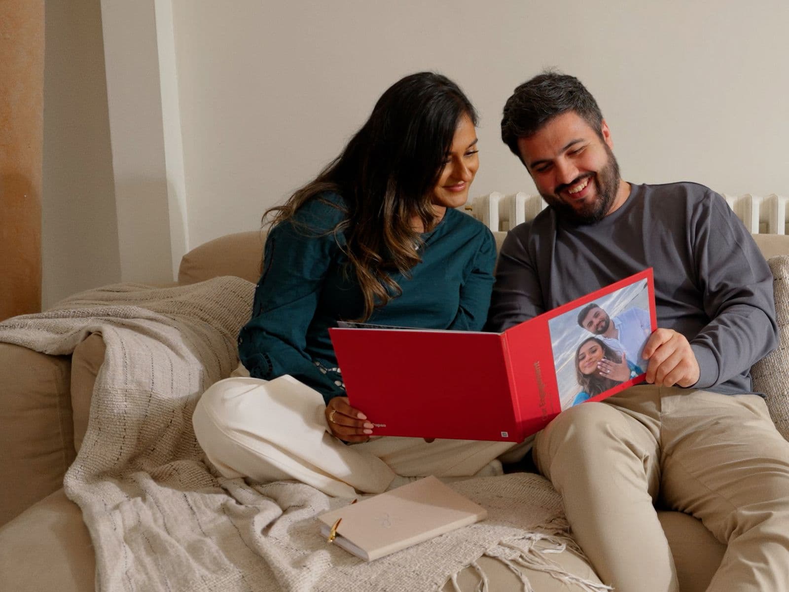 A newly engaged couple sit flicking through their engagement photo book