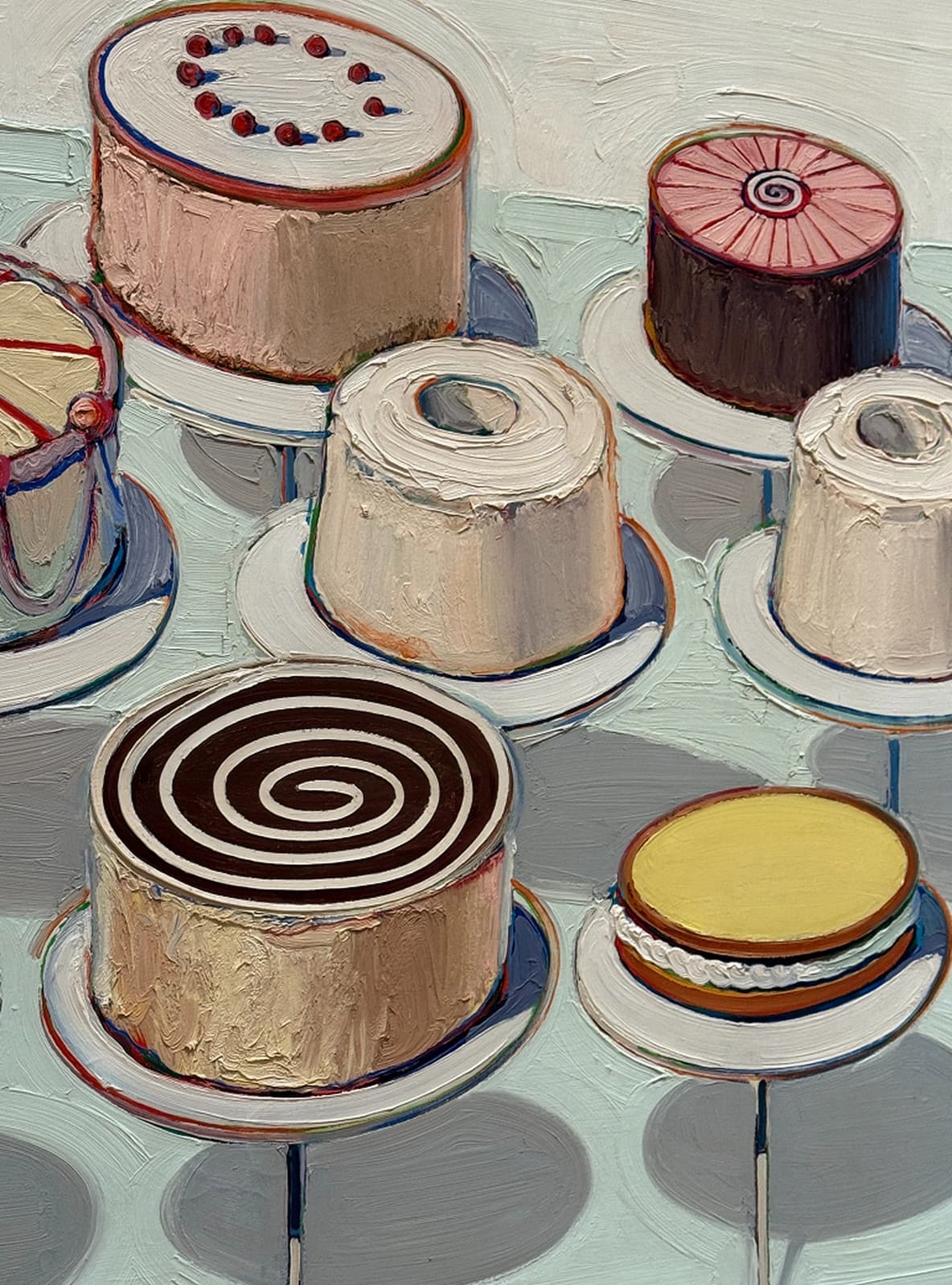 A collection of round cakes with various designs, including spirals and dots, displayed on white pedestals against a light background.