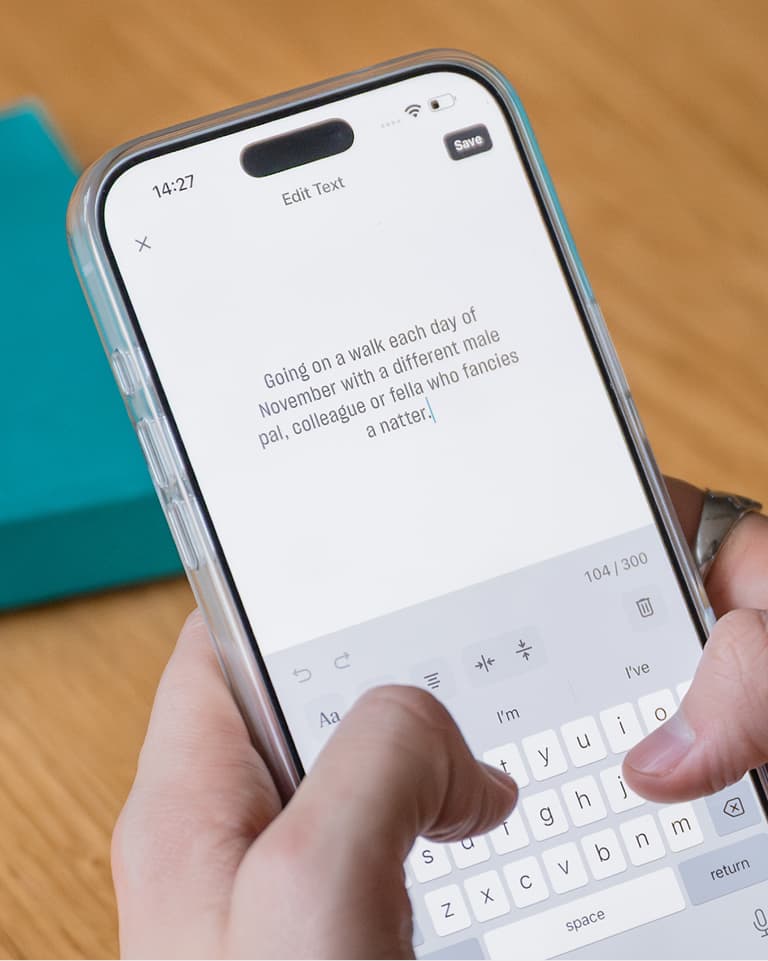 Hands holding a smartphone showing a note about going on walks each day in November with different male friends.