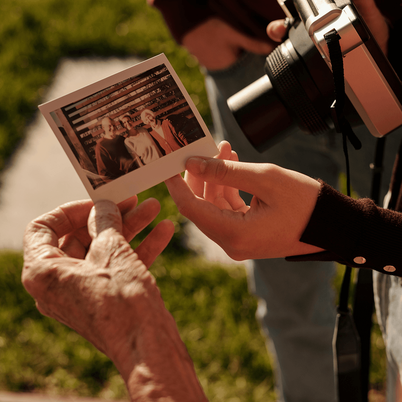 Hands holding an instant photo of two people, with a vintage camera visible in the background