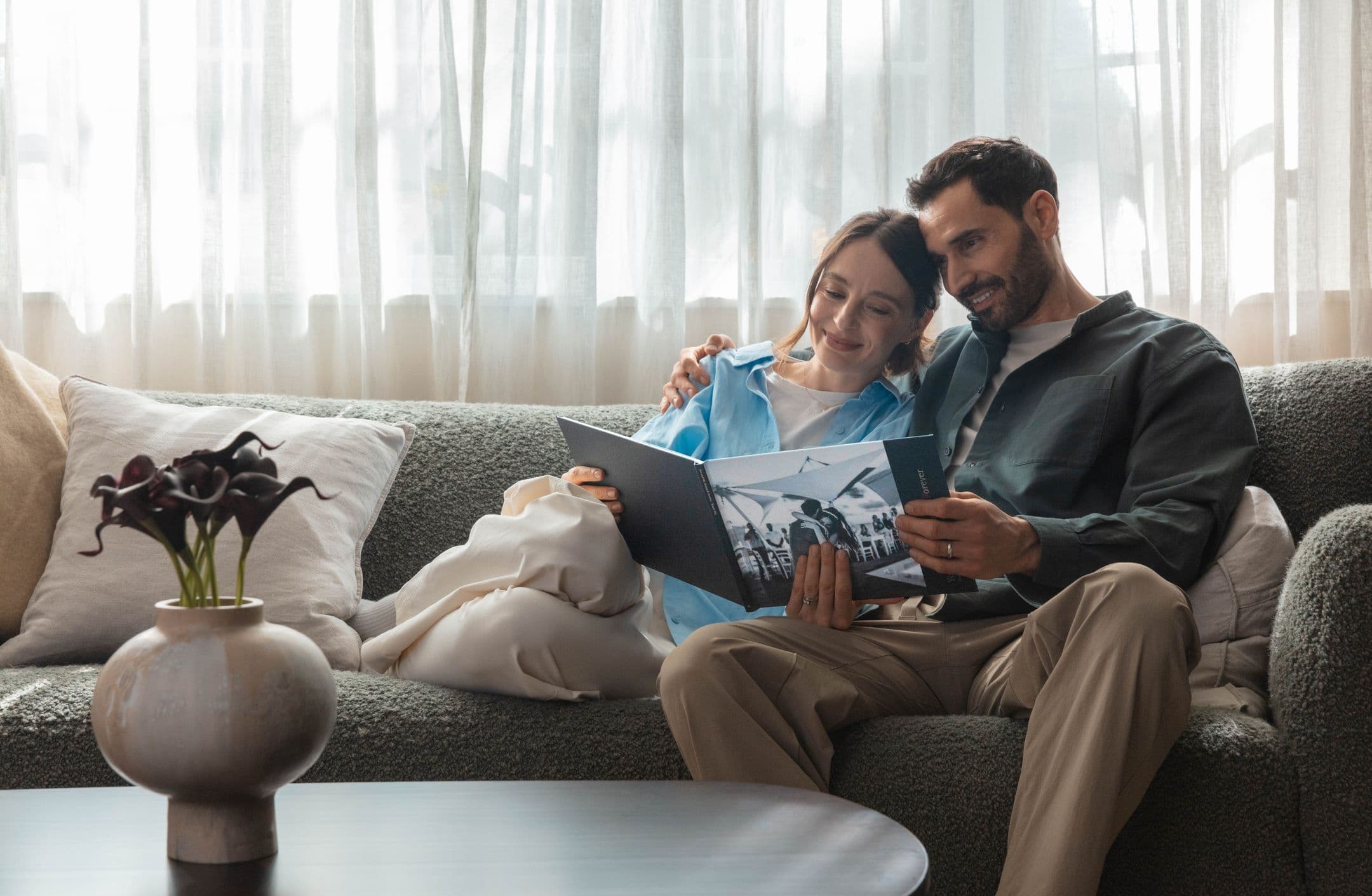 Newlyweds sit on a sofa looking through their wedding photo book