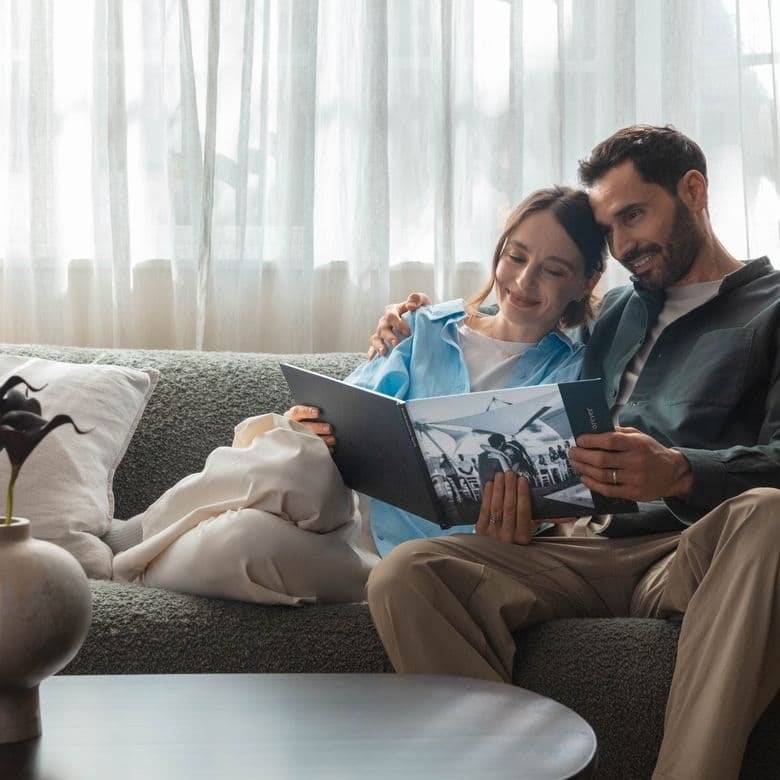 Newlyweds sit on a sofa looking through their wedding photo book