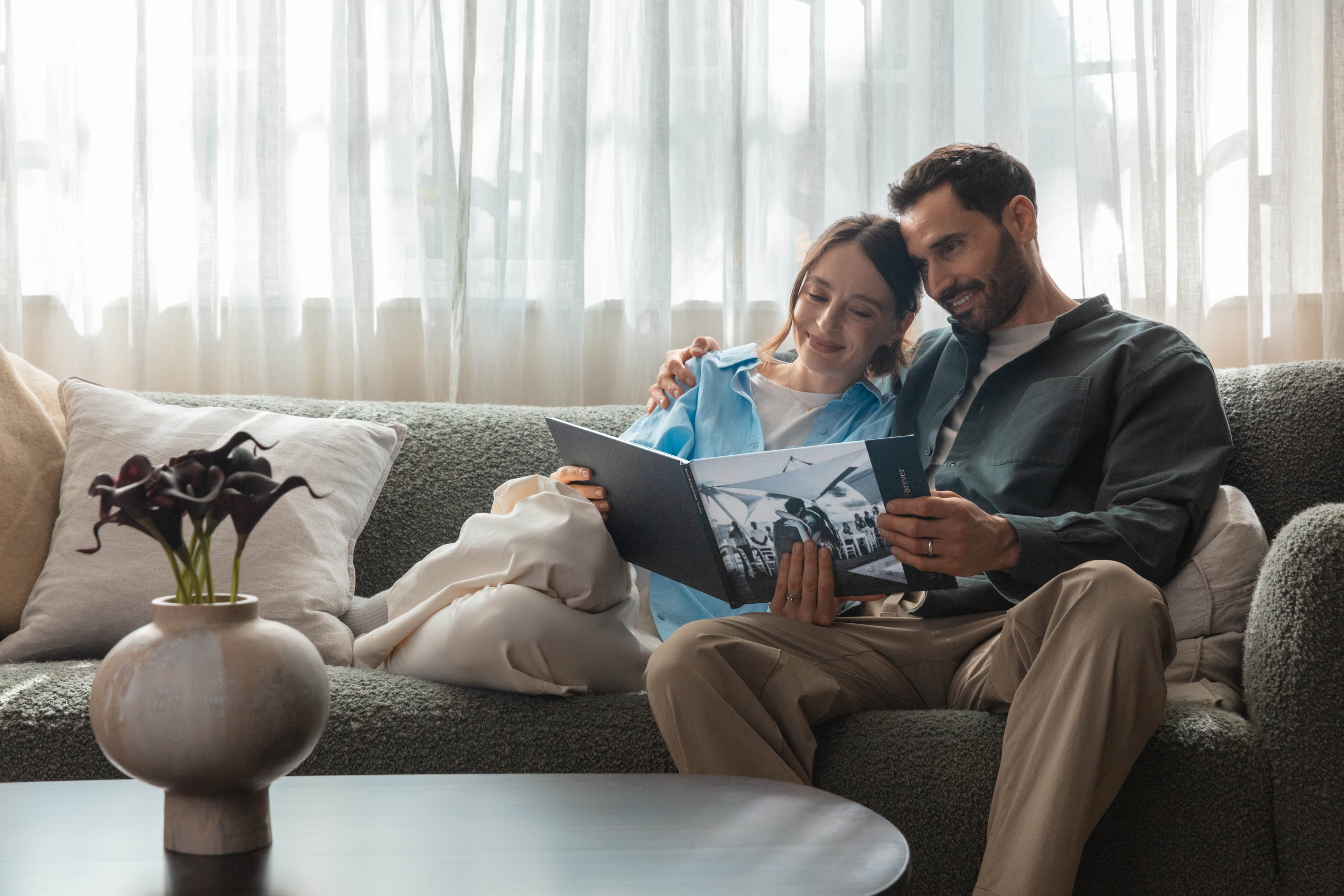 Newlyweds sit on a sofa looking through their wedding photo book