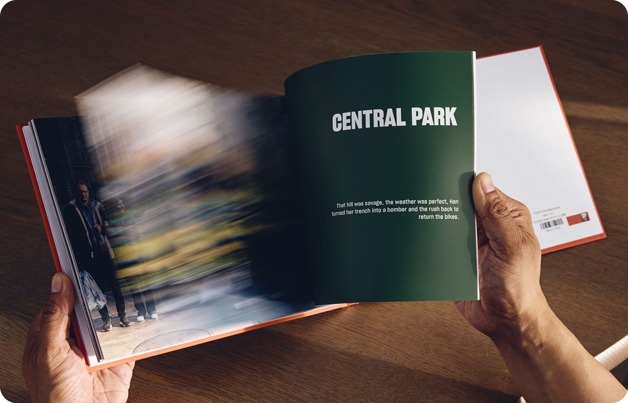 Hands holding an open book with a blurred left page and a right page titled "CENTRAL PARK" on a wooden surface.
