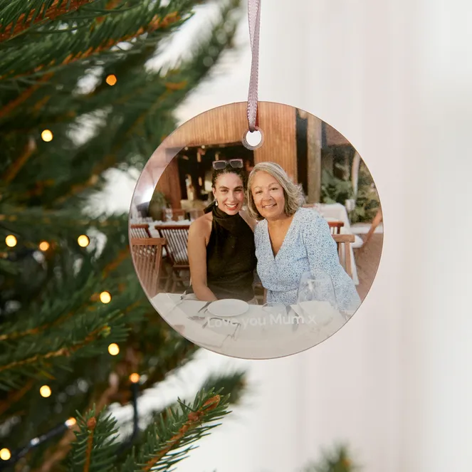 A Christmas tree decorated with a maroon ornament and a round photo ornament featuring two people with the text "Love you Mum x."