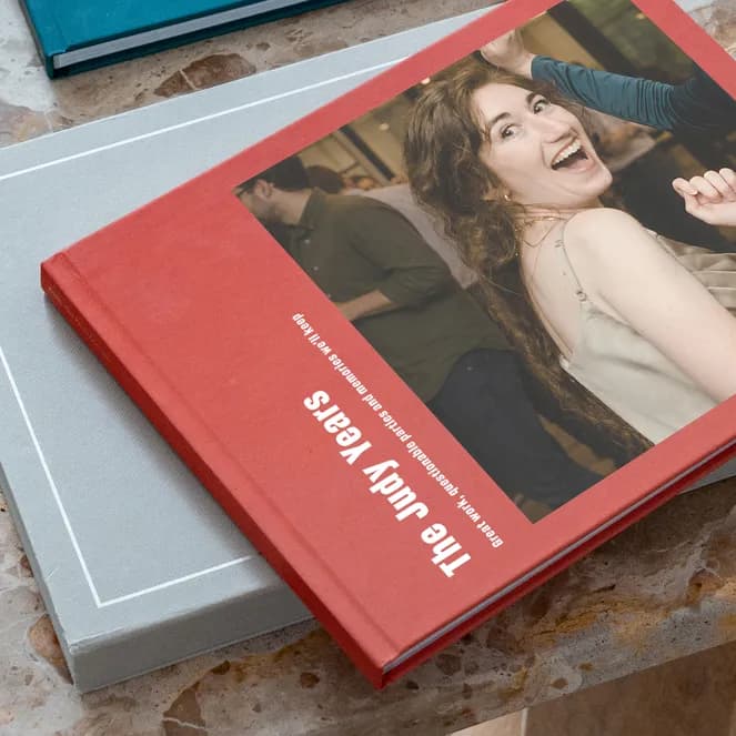 A red book titled "The Judy Years" with a joyful woman on the cover, placed on a gray book atop a marbled surface.