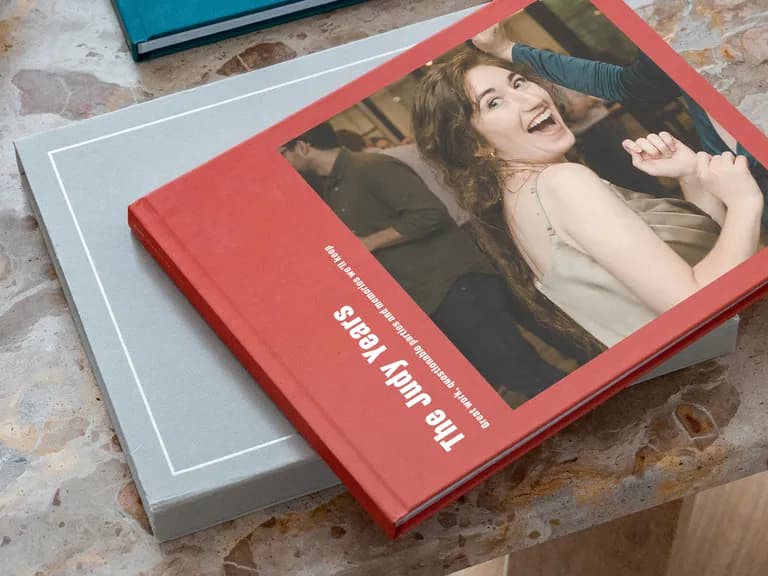 A red book titled "The Judy Years" with a joyful woman on the cover, placed on a gray book atop a marbled surface.
