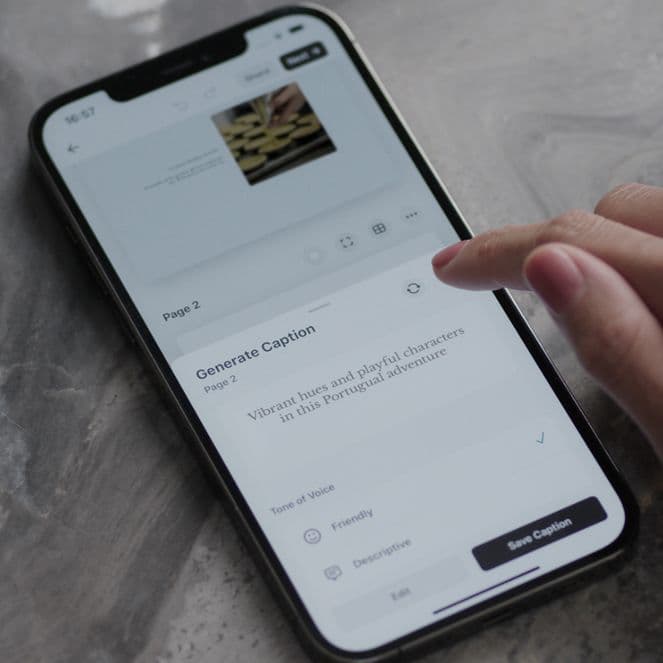 Hand interacting with a smartphone on a marble surface, displaying a caption generation app. A glass of water is nearby.