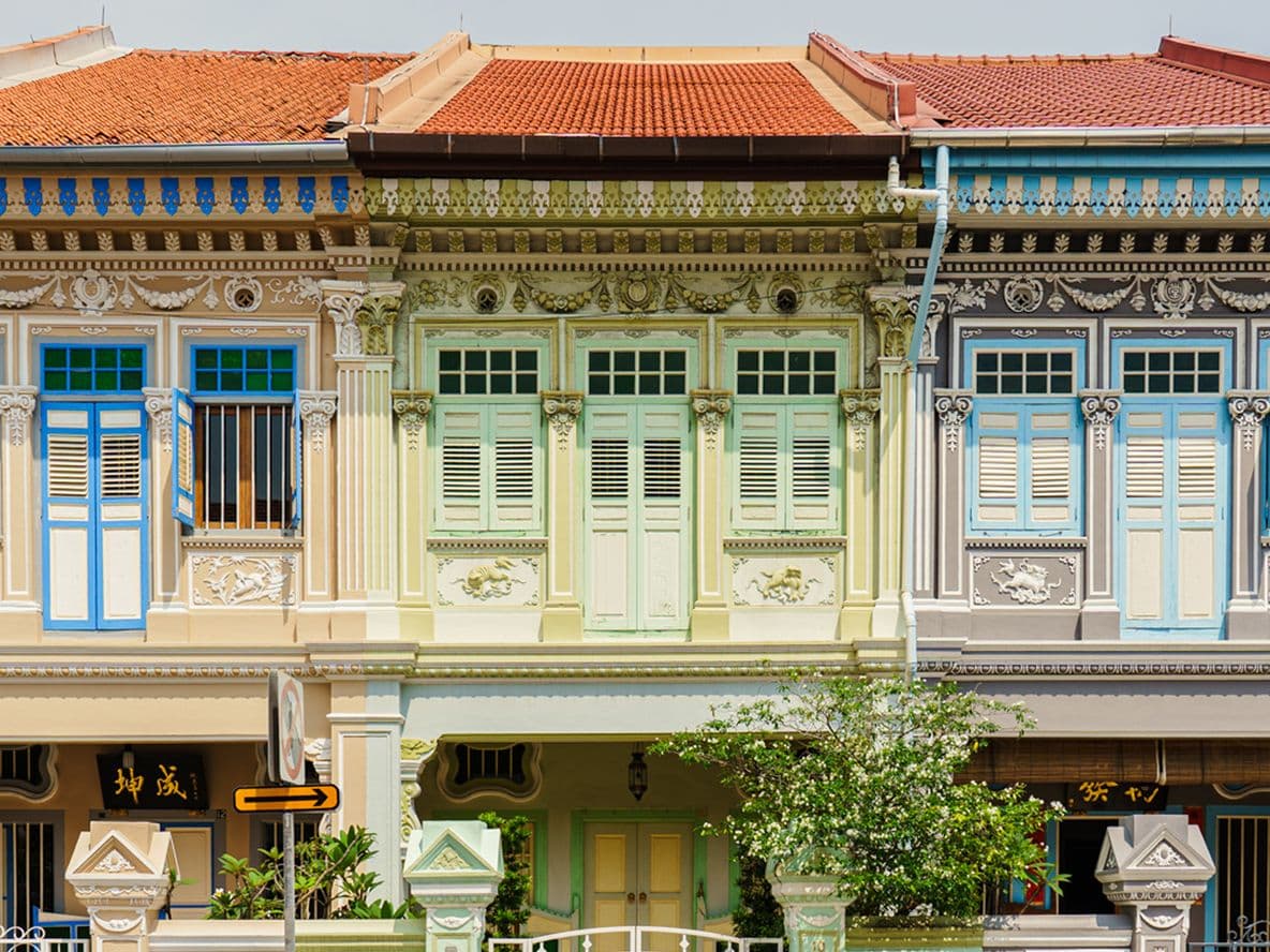 Colorful, ornately decorated row of shophouses with intricate details and pastel hues.