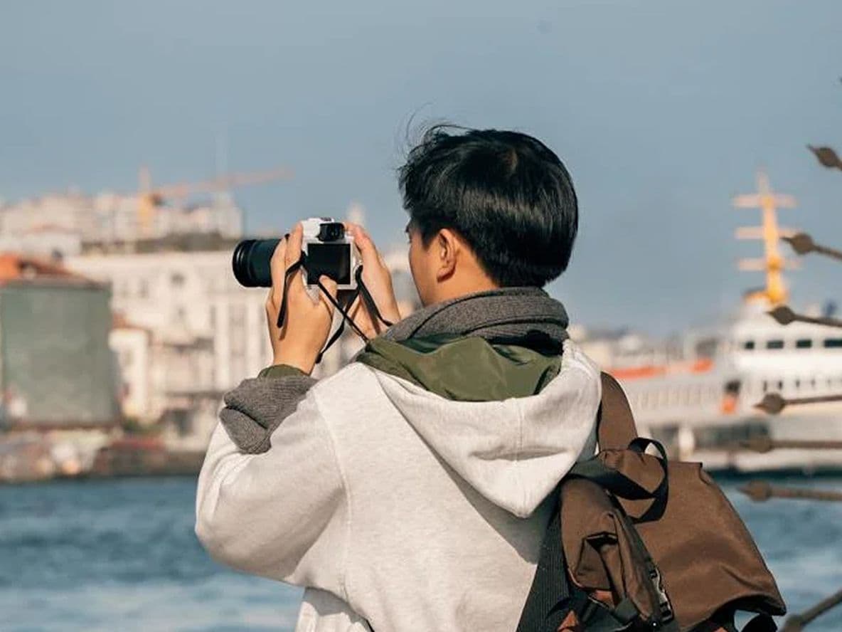 A tourist taking photos of a city across a body of water