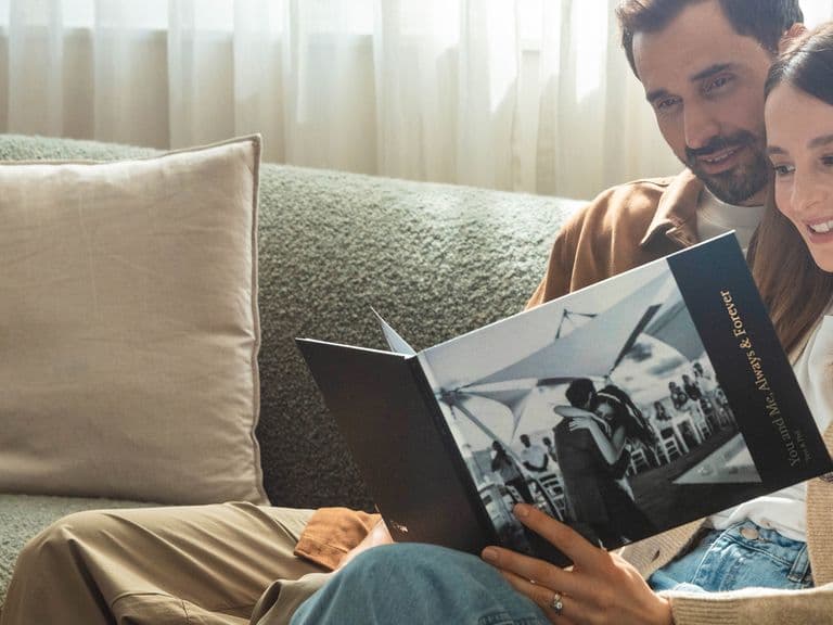 A couple looking at a hardcover photo book of their wedding