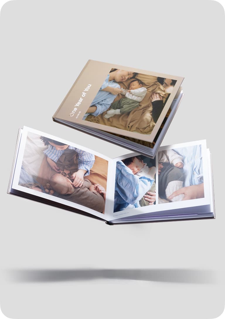 Two photo books with family images; one closed on top, one open showing pictures of a child and parents. Light gray background.
