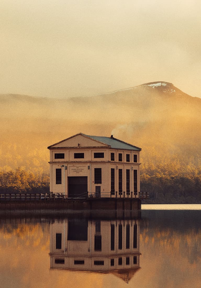 Steam rises above a house reflected in a lake in autumn