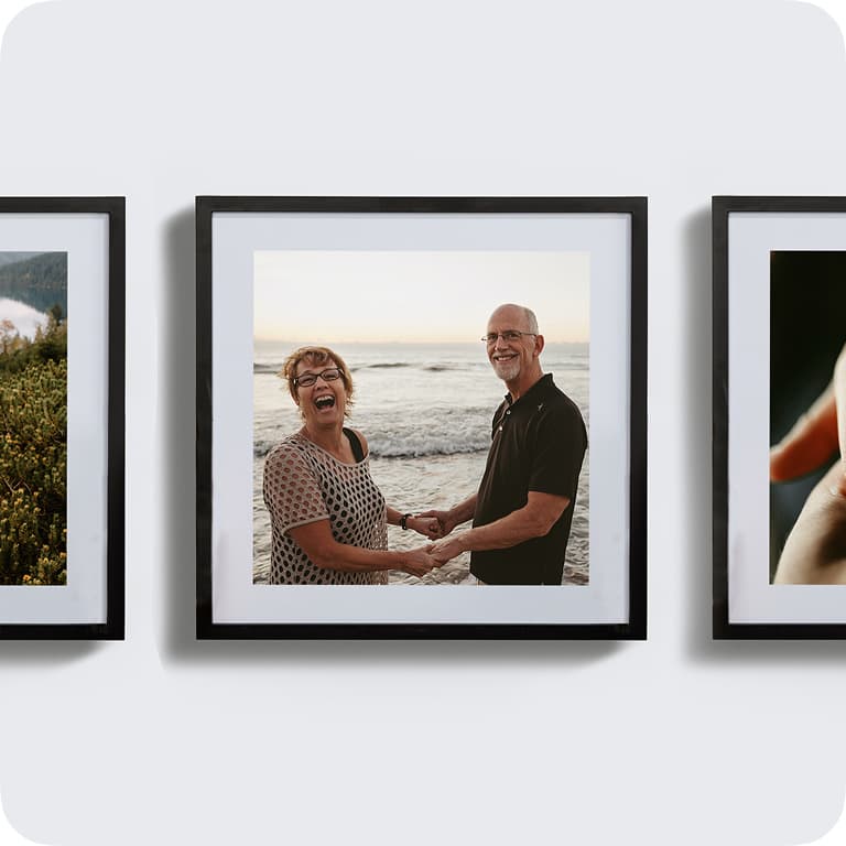 Framed photo of a smiling couple holding hands on a beach, with waves in the background.
