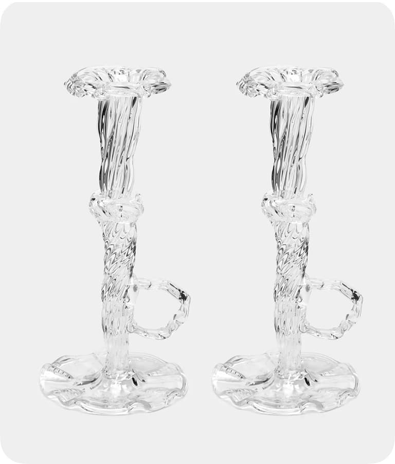 Two ornate, transparent glass candlesticks with twisted stems and decorative bases, set against a plain white background.