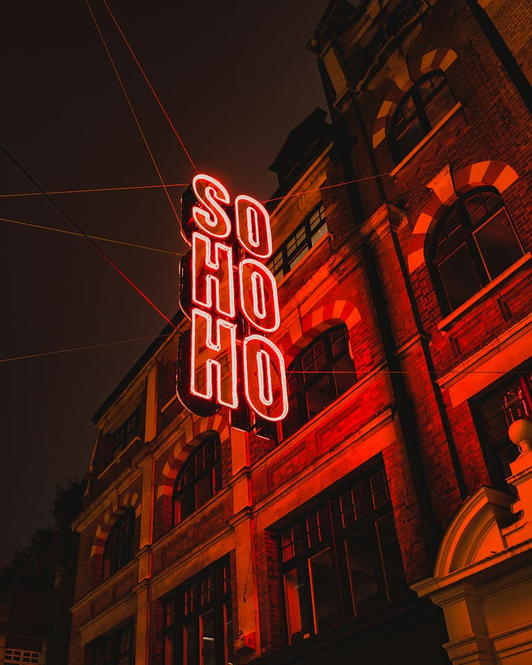 Neon Soho sign draped above street in London