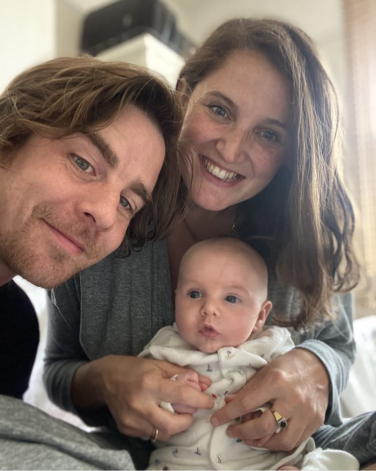 Couple smiling holding their baby