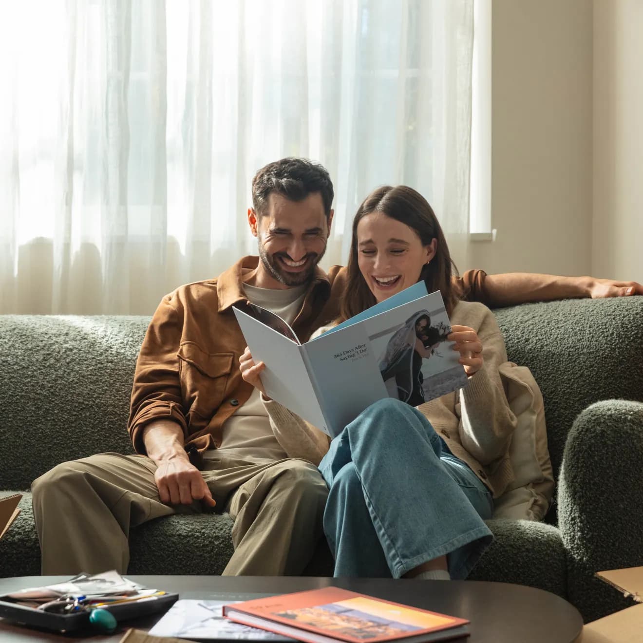 A married couple looking back at their wedding photos in an anniversary photo book on a sofa